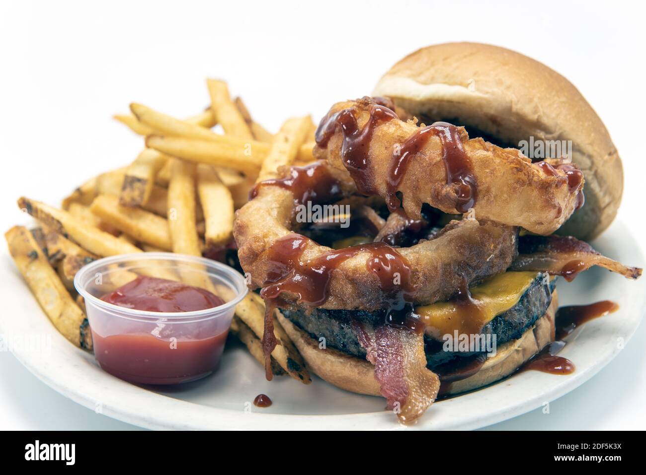 Riesige Zwiebelringe beträufelt mit Barbecue-Sauce auf Hamburger serviert mit pommes Frites und Dipping Sauce. Stockfoto