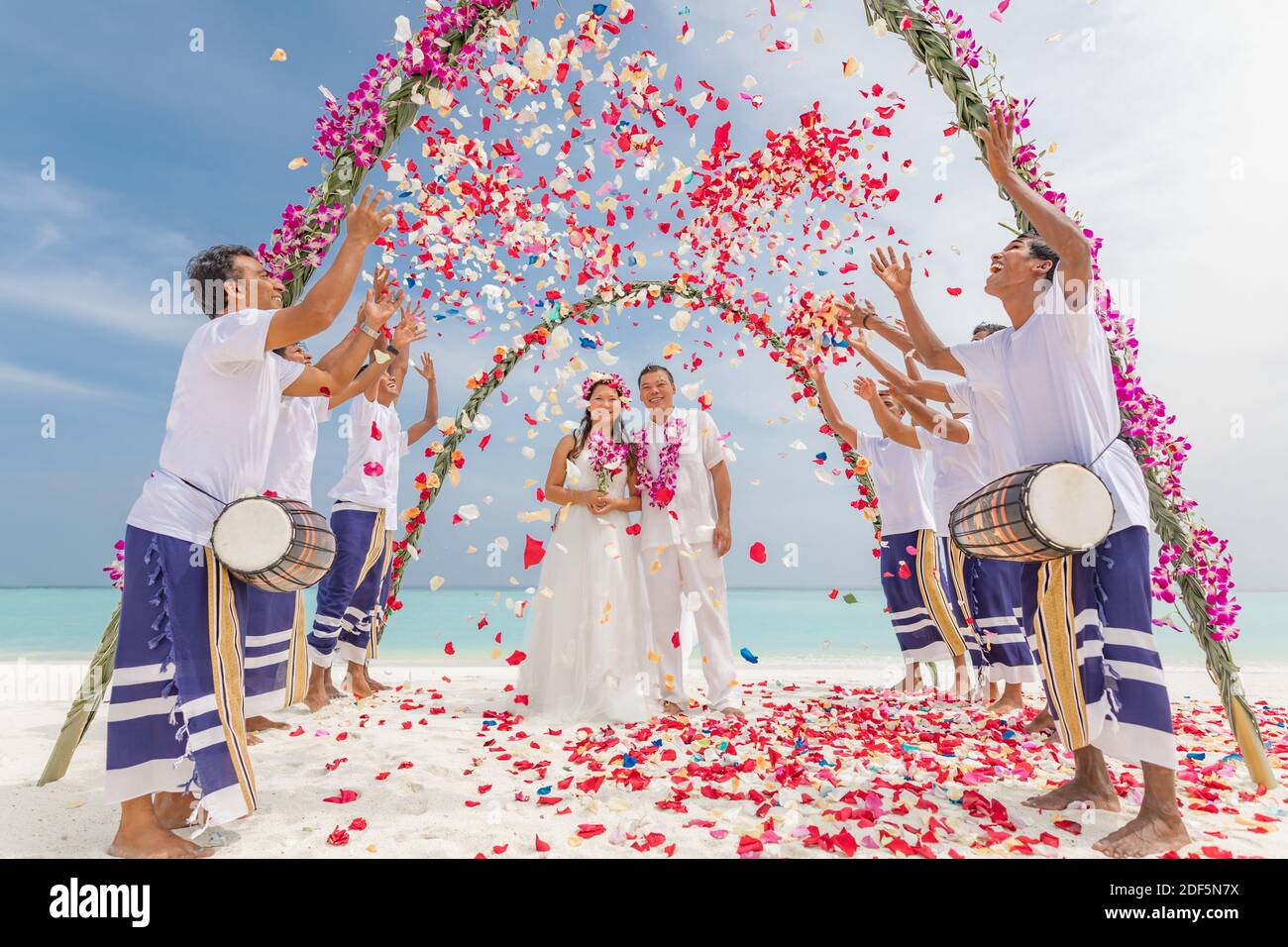 10.08.19 Inseln der Malediven. Junge asiatische paar küssen bei Hochzeitsempfang unter Blumen. Liebe Romantik Hochzeitszeremonie weißen Sandstrand in der Nähe des Meeres Stockfoto