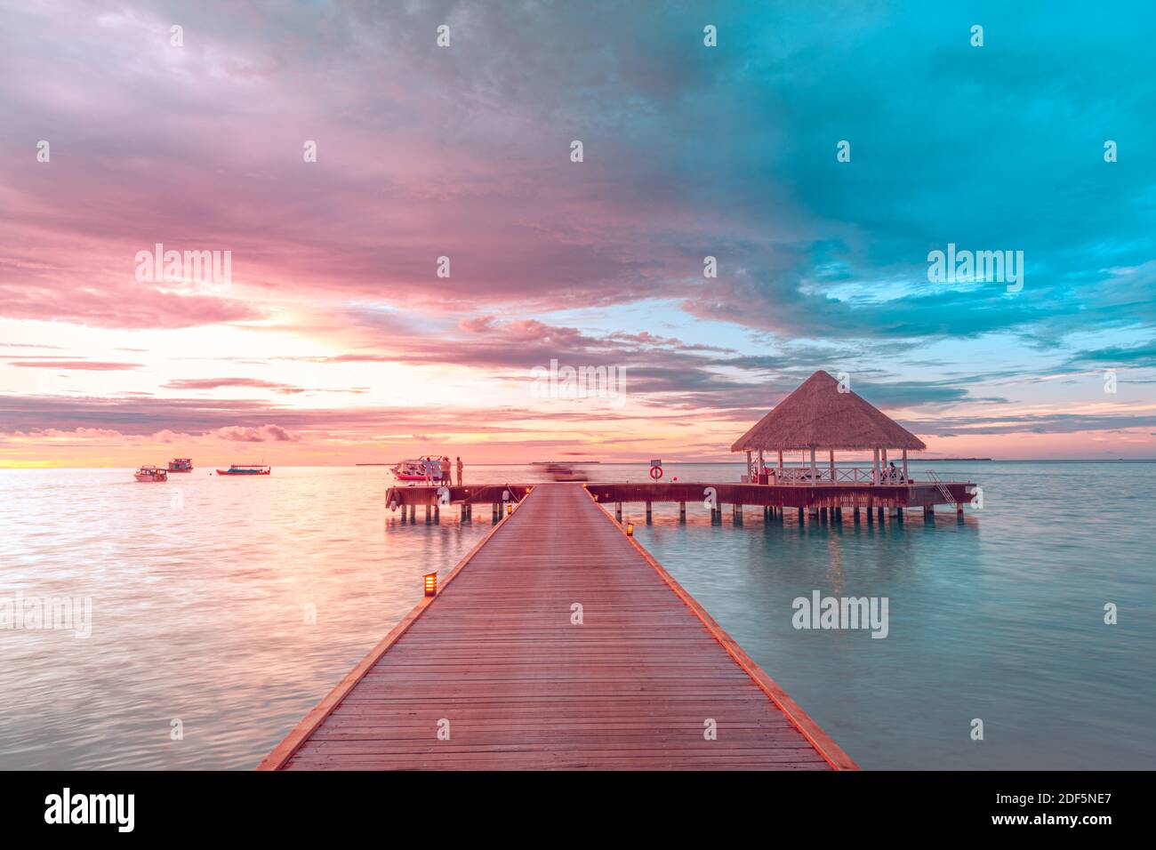 Sonnenuntergang auf den Malediven Insel, Luxus Water Villas Resort und hölzernen Pier. Schönen Himmel und Wolken und Strand Hintergrund für Sommer Urlaub Stockfoto