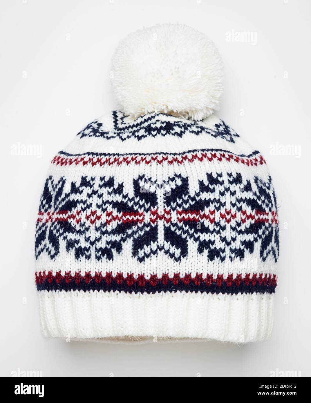 Weiß gestrickt Winter Bommel Hut mit skandinavischen geometrischen Ornament verziert. Handgefertigte Wollmütze mit Bommel auf der Oberseite Stockfoto