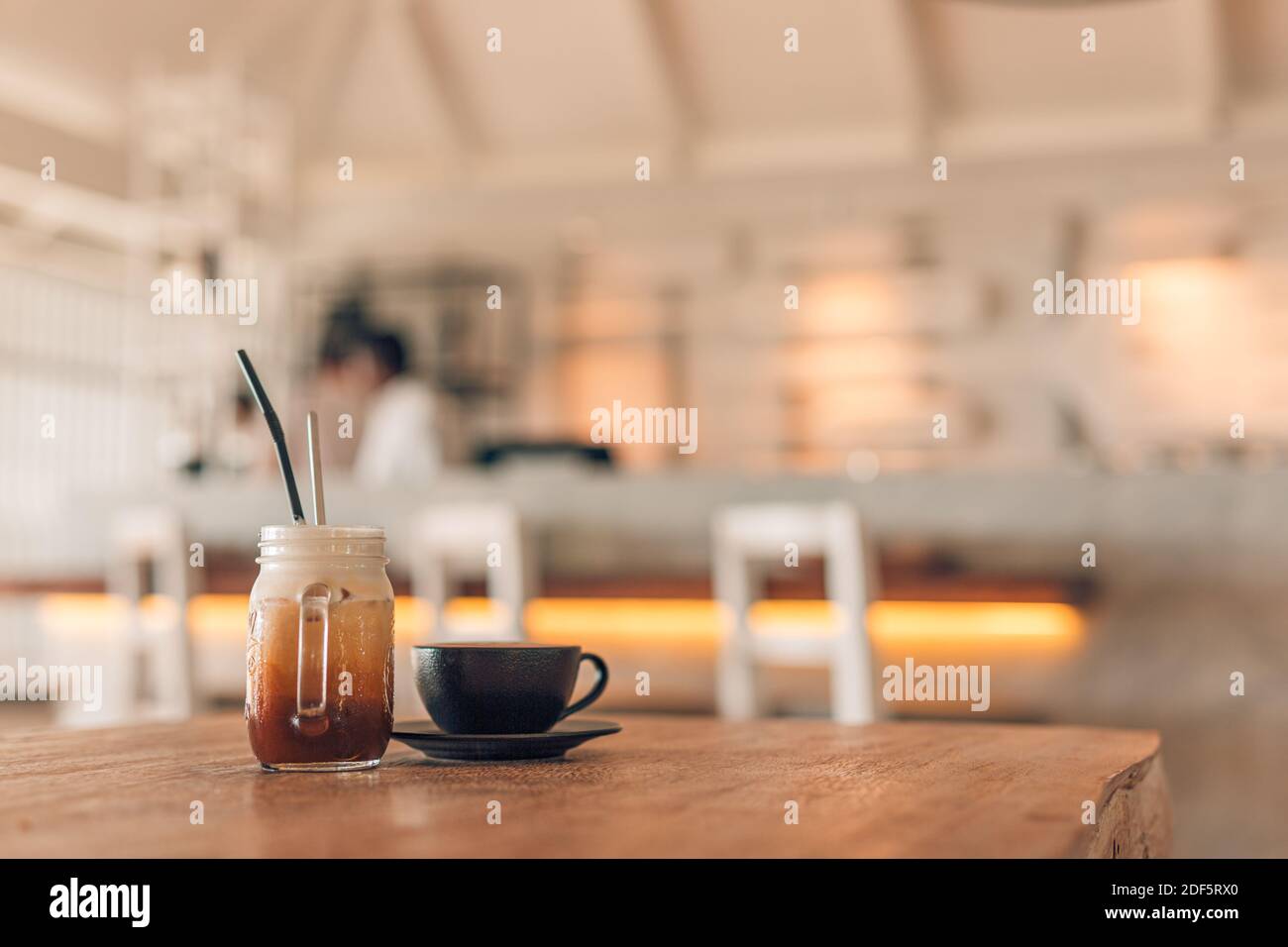 Iced Latte Kaffeeglas mit Latte in dunklem Becher auf Holztisch im Restaurant und Café verschwommener Hintergrund, Kopierraum für Text Stockfoto