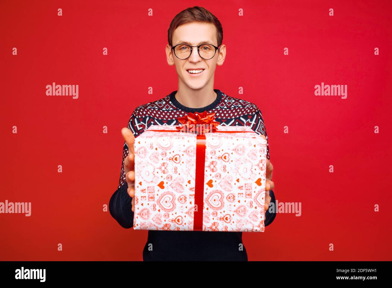 Ein Mann mit Brille reicht eine Geschenkbox Die Kamera Stockfoto