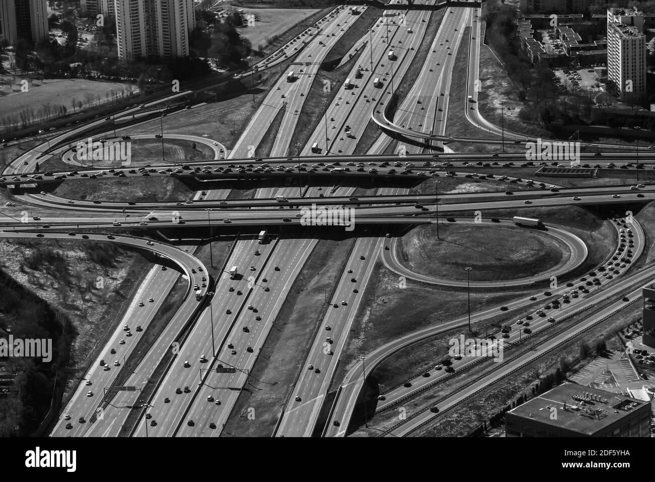Eine Luftaufnahme in Graustufen von einer städtischen Stadtautobahn und Überführung ist voll mit Verkehr Stockfoto