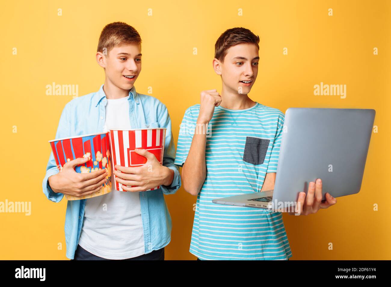 Zwei Teenager-Freunde mit einem Eimer Popcorn in ihrem Hände und ein Laptop, der sich auf das Ansehen von Filmen vorbereitet Stockfoto
