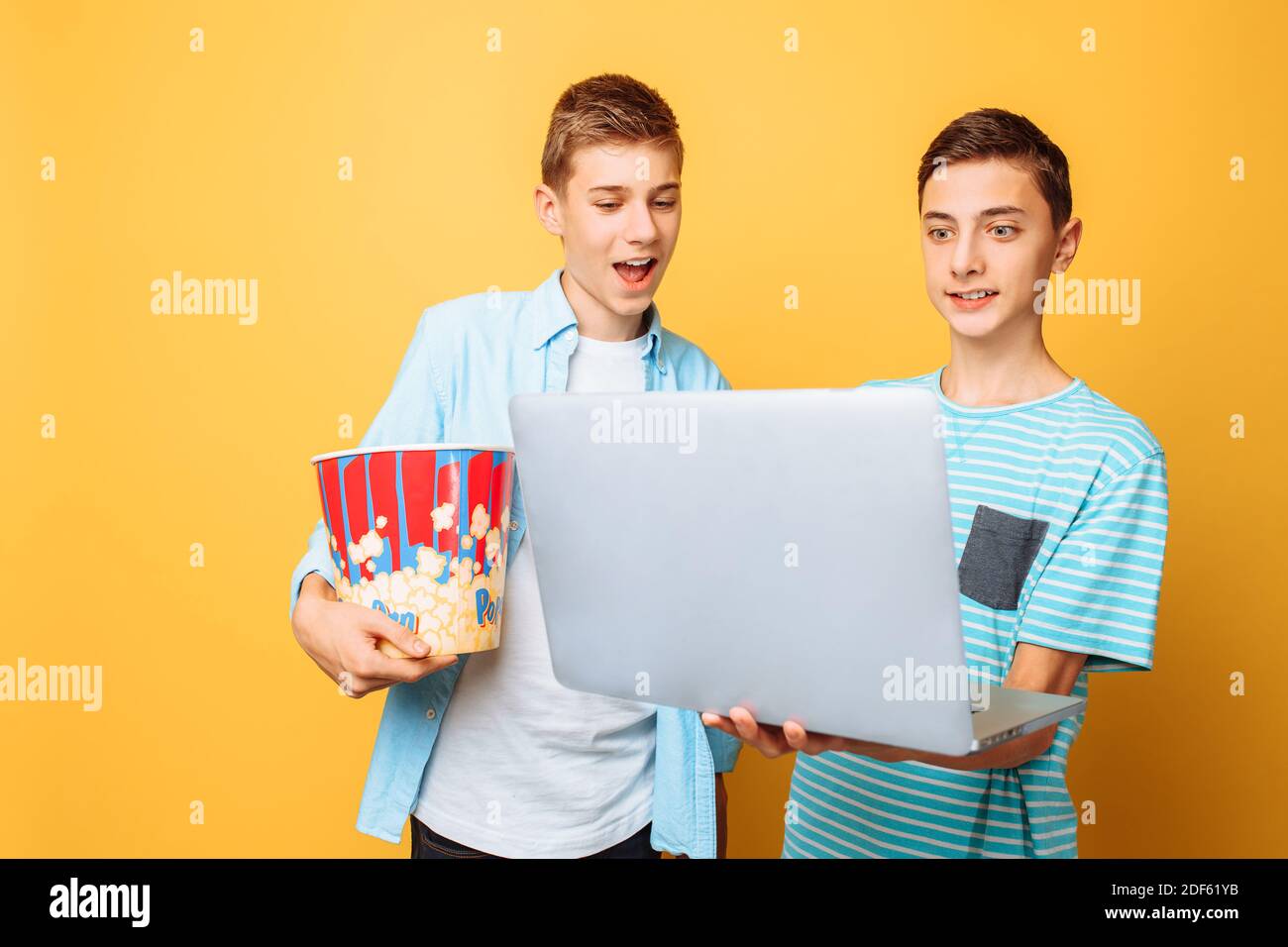 Zwei Teenager-Freunde mit einem Eimer Popcorn in ihrem Hände und ein Laptop, der sich auf das Ansehen von Filmen vorbereitet Stockfoto