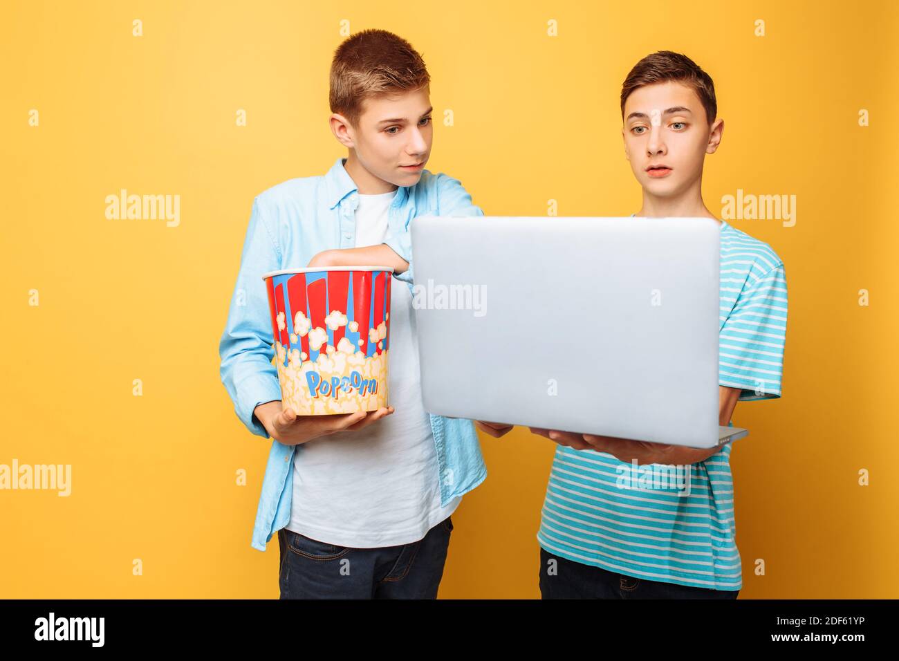 Zwei Teenager-Freunde mit einem Eimer Popcorn in ihrem Hände und ein Laptop, der sich auf das Ansehen von Filmen vorbereitet Stockfoto