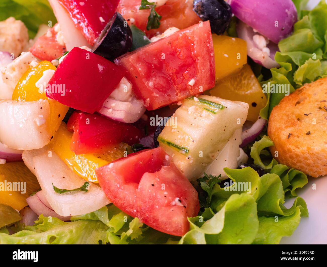 Weißer Teller mit griechischem Salat und Scheibe Knoblauchbrot. Stockfoto