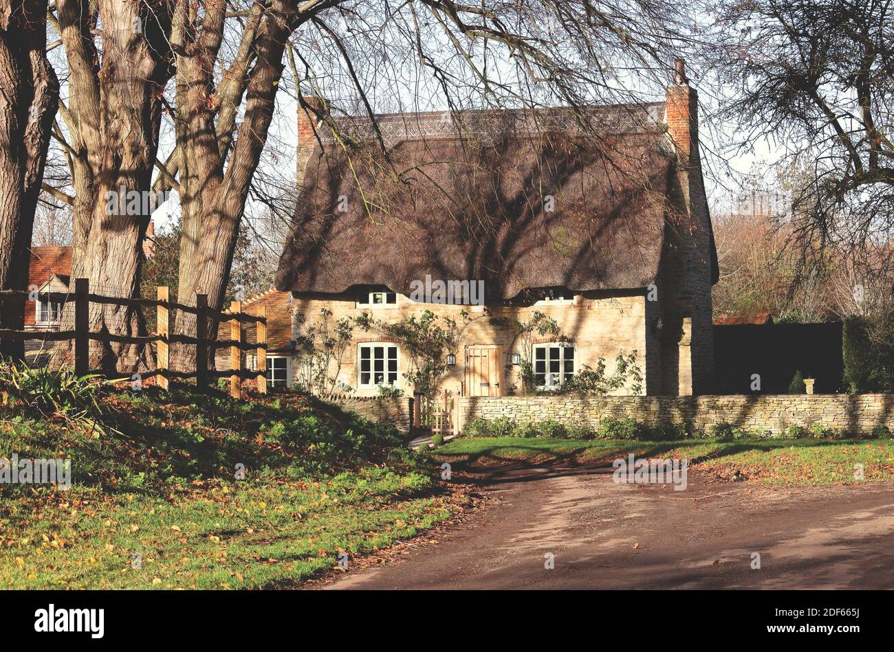 Traditionelles, aus Stein gebautes, reetgedeckten English Village Cottage mit strahlendem Sonnenschein Auf der Spur Stockfoto