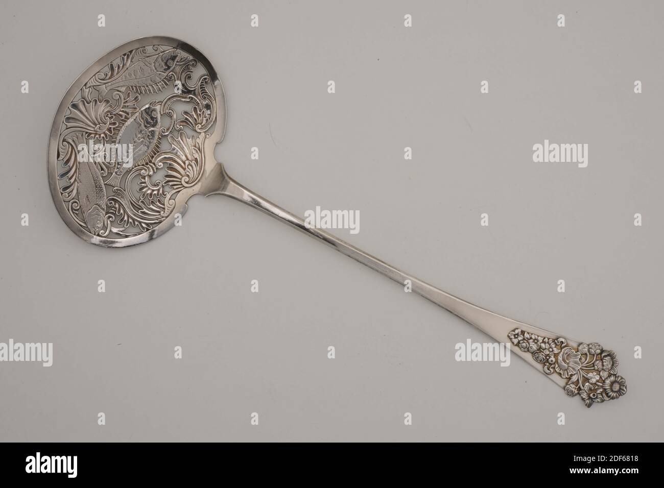 Schaufel (Serviermaterial), Hendrik Fortman, 1772, Allgemein: 38.6 x 13.8 x 2,4 cm (386 x 138 x 24 mm), Blume, Fisch, ovaler Silberfischlöffel mit langer, flacher Verjüngerung und am oberen Rand abgeschrägter Stiel. Auf dem breiten Ende ist ein gegossenes und graviertes Blumenmotiv, bestehend aus einer Schale mit einer Pflanze mit blühenden Blumen an der Oberseite und zwei Bändern und hängenden Blumentrinde an der Unterseite. Der Löffel hat ein doppeltes Lob. Die auf dem Stiel ausgehöhlte Schaufel hat drei Fische, die in einem Dreieck zwischen dem Rokoko-Ornament gruppiert sind. Auf der Rückseite markiert, 1949 Stockfoto