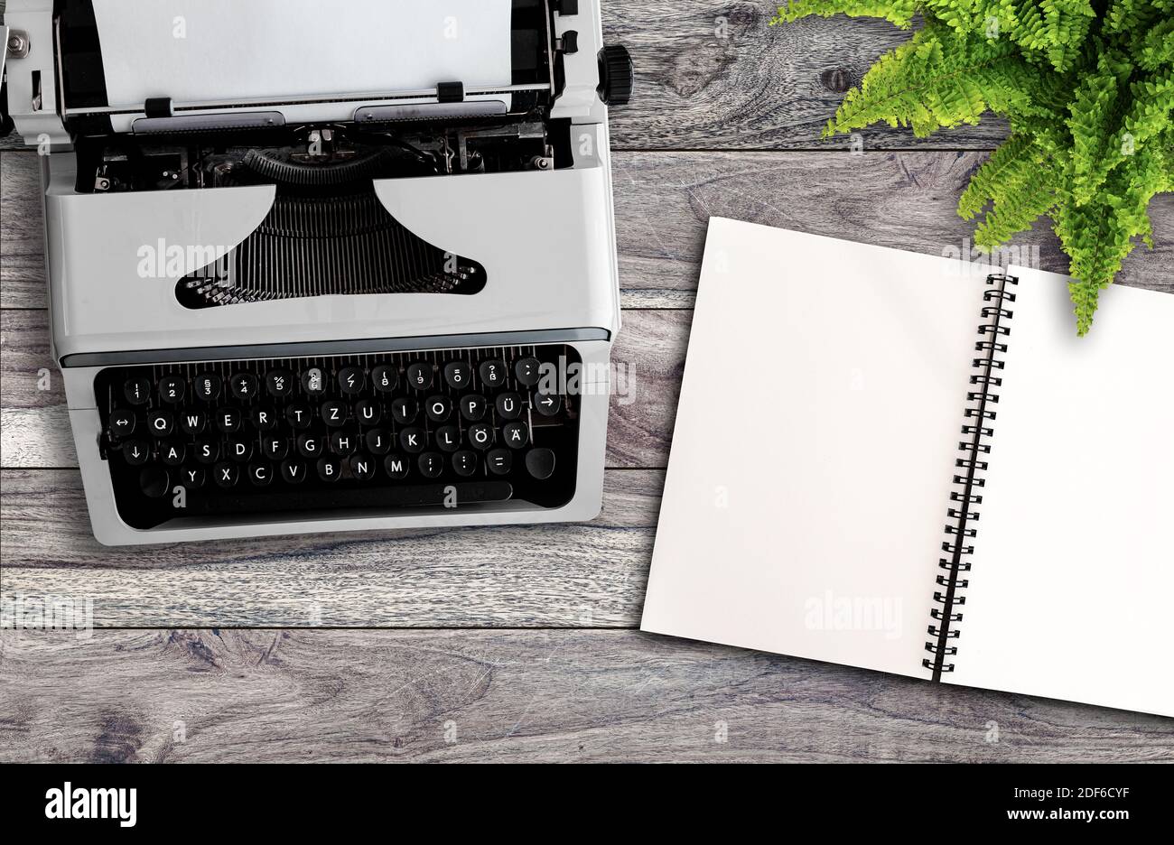 Blogging- oder Schreibkonzept, direkt über Ansicht der alten Schreibmaschine und leerer offener Notizblock auf Holzschreibtisch Stockfoto