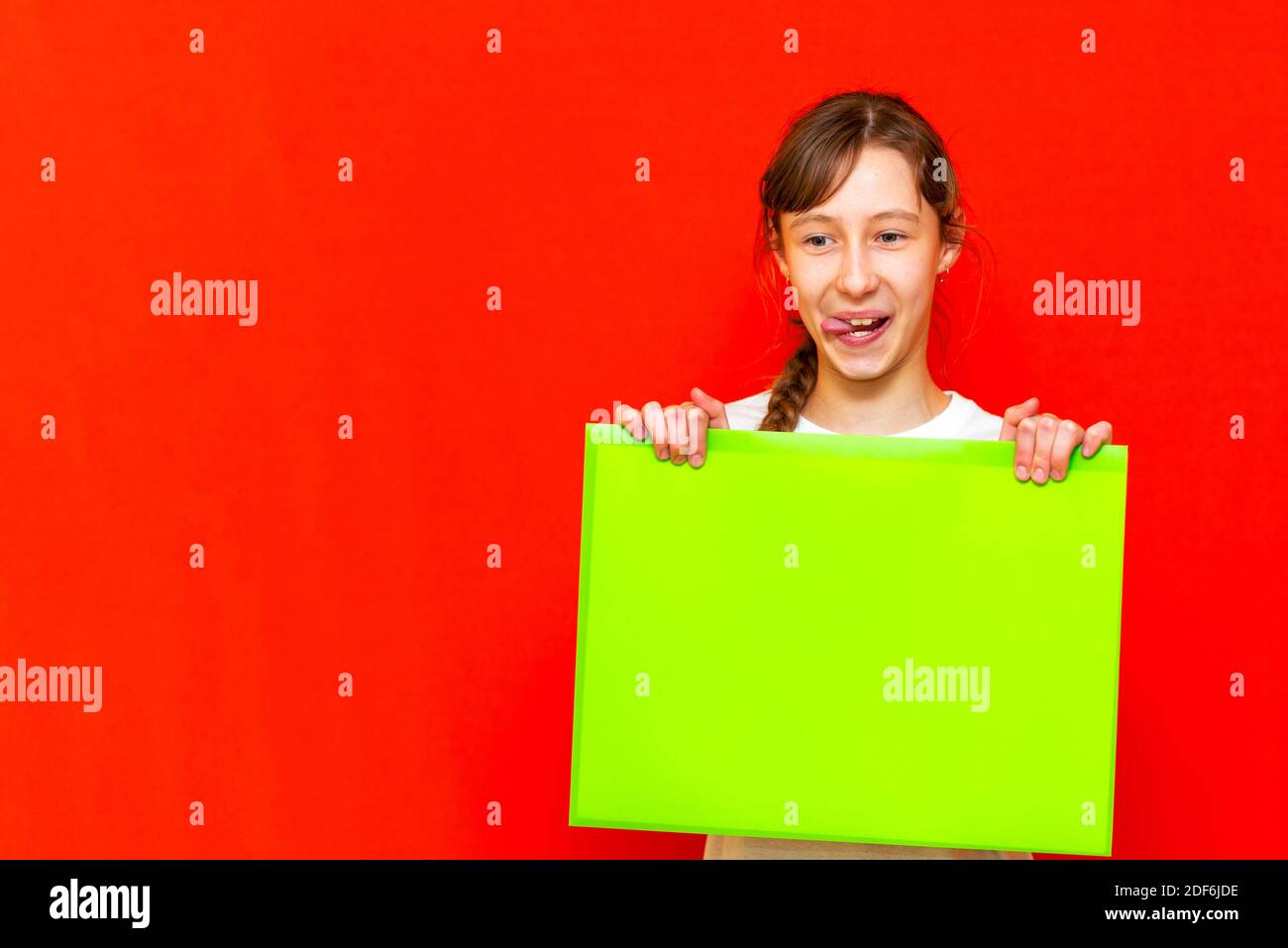 Junge selbstzufrieden kaukasischen Teenager Mädchen mit leerem Papier Blatt über roten Studio Hintergrund. Stockfoto