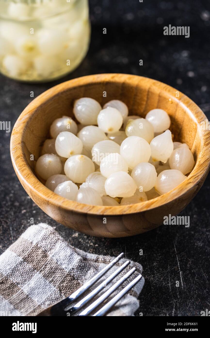 Eingelegte Mini-Babyzwiebeln in Holzschüssel. Stockfoto