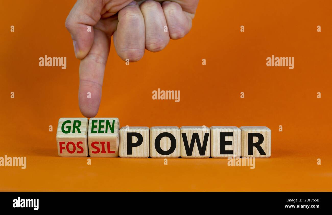 Grom fossil zu grüner Energie. Männliche Hand dreht Würfel und ändert die Wörter "fossile Energie" zu "grüne Energie". Schöner orangefarbener Hintergrund. Business und gre Stockfoto