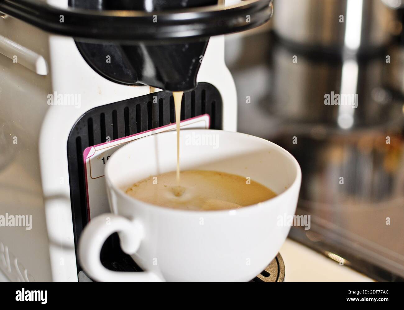 Nahaufnahme einer Tasse Cappuccino-Kaffee an der Espressomaschine. Vorderansicht. Stockfoto