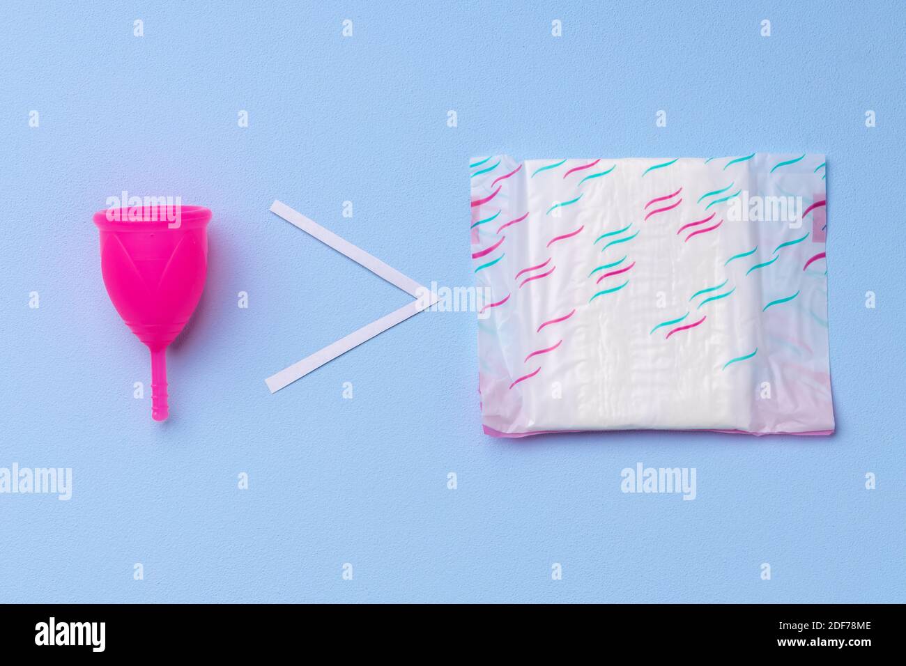 Menstruationstasse und Hygienepad auf Papier Hintergrund Stockfoto