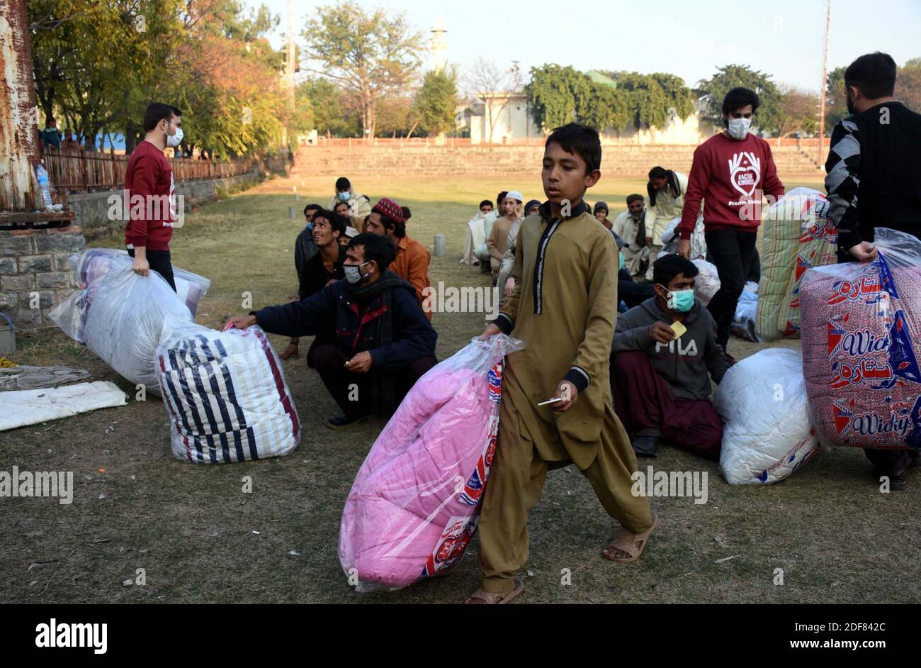 Freiwillige der Praxis Güte verteilen Quilts / Decken unter obdachlosen Arbeitern während der Verteilungszeremonie auf G-9/1 Cricket Ground in Islamabad am Donnerstag, 3. Dezember 2020. Stockfoto