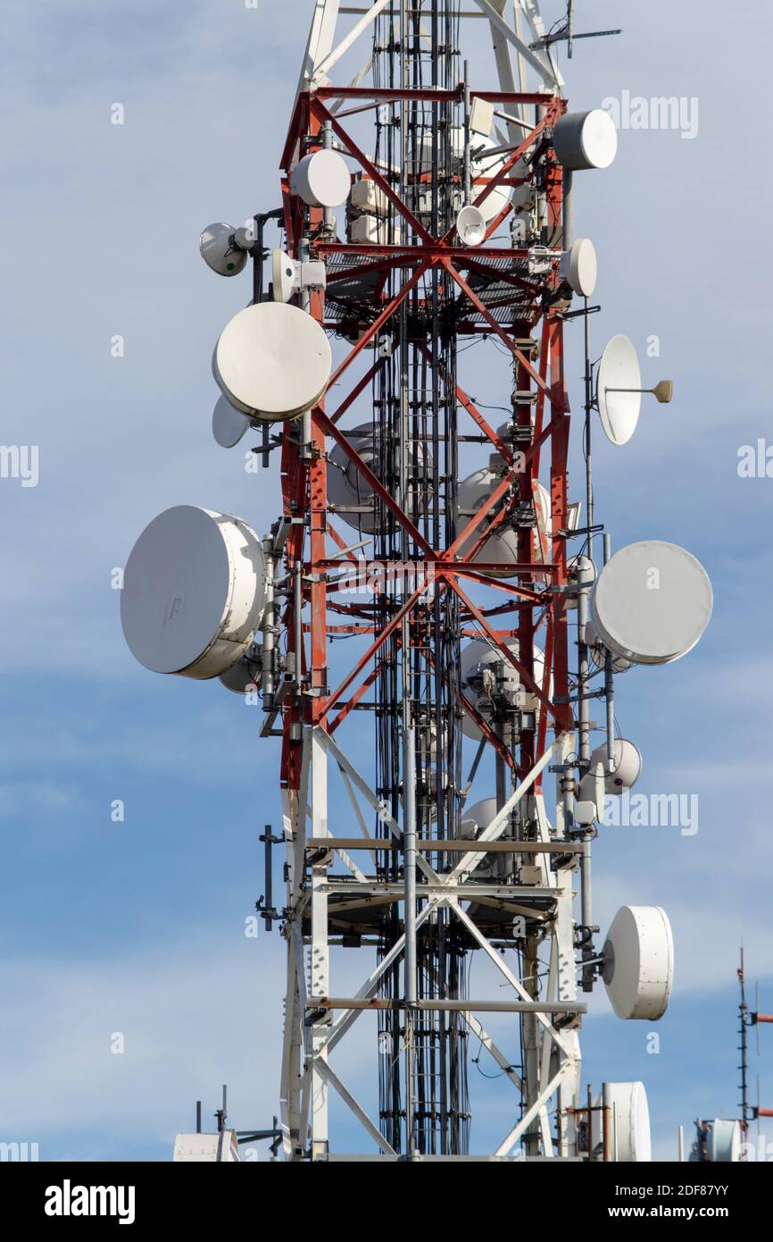Rot-weißer Telekommunikationsturm mit Satellitenantennen und Kommunikationsgeräten. Stockfoto