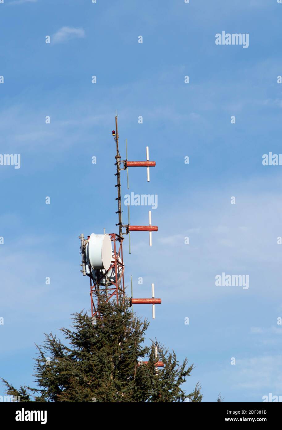 Rot-weißer Telekommunikationsmast mit Satellitenantennen. Fichte und mobiler Turm. Stockfoto