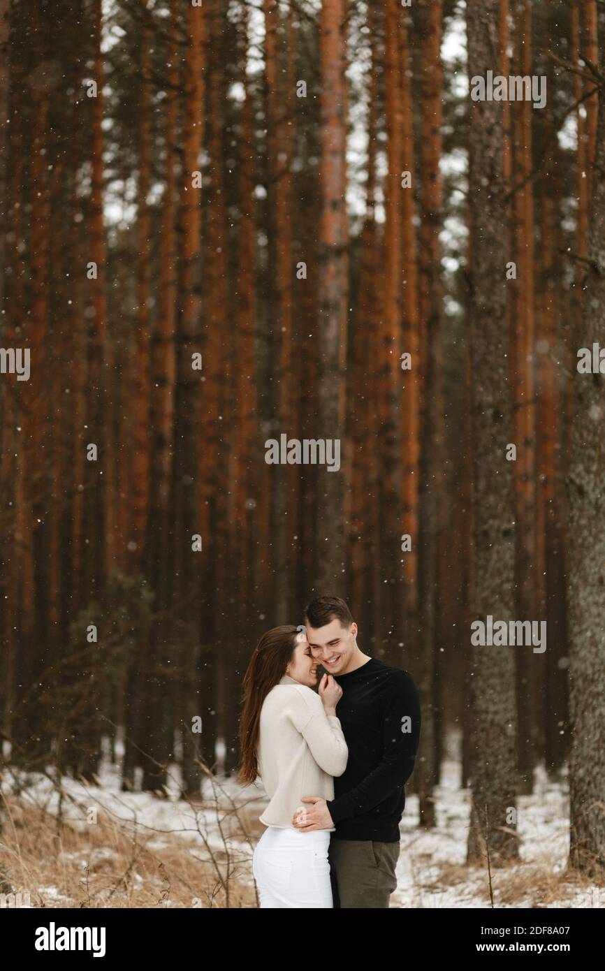 Schönes Paar umarmt am Hintergrund des Winterwaldes mit dem Ort für Ihren Text. Beziehung, Winterferien. Winter paar Foto-Ideen Stockfoto