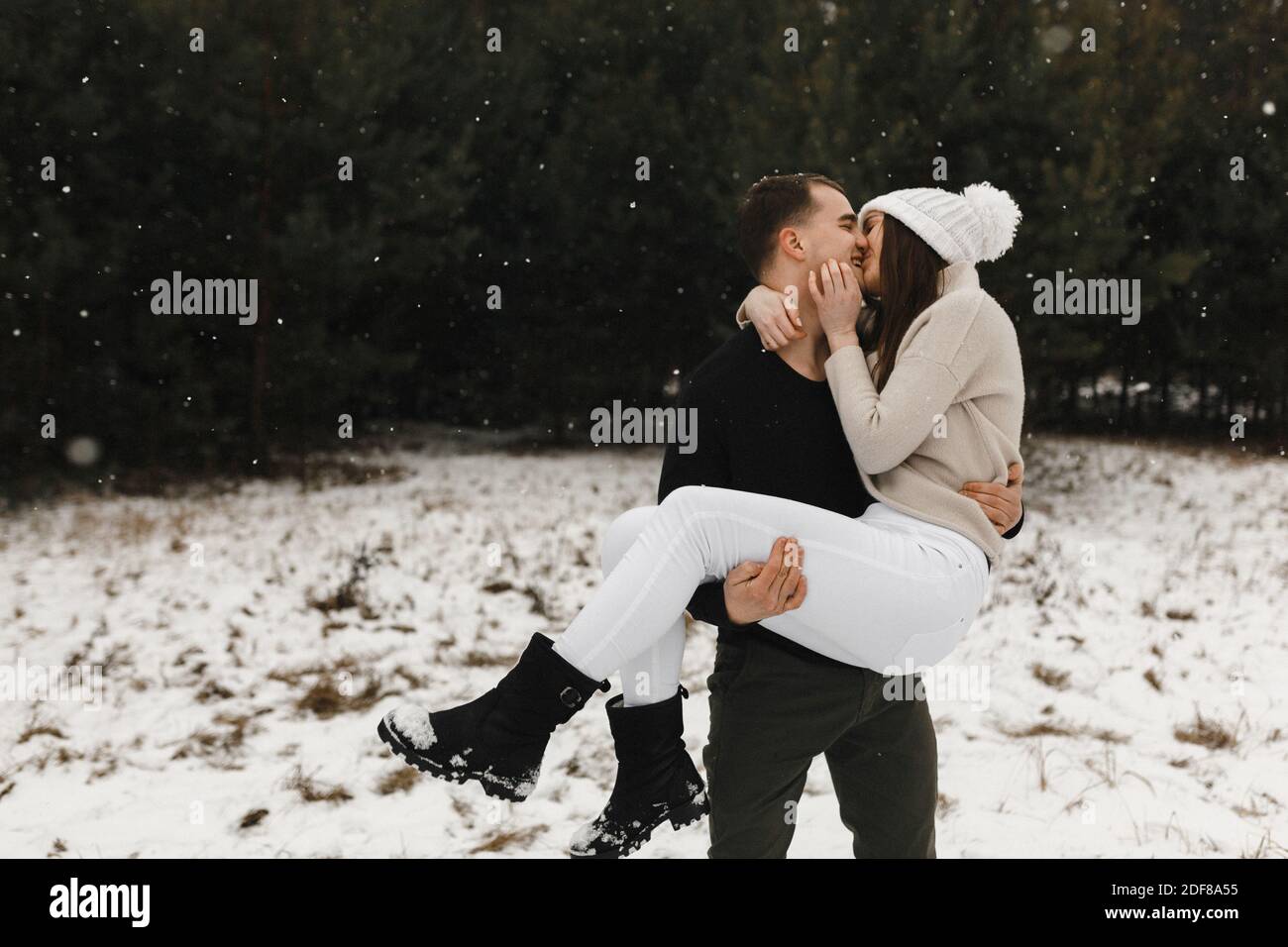 Mann hält Frau in den Händen und küsst sie im Winterwald. Ort für Ihren Text. Liebe, Beziehung, Winterurlaub. Stockfoto