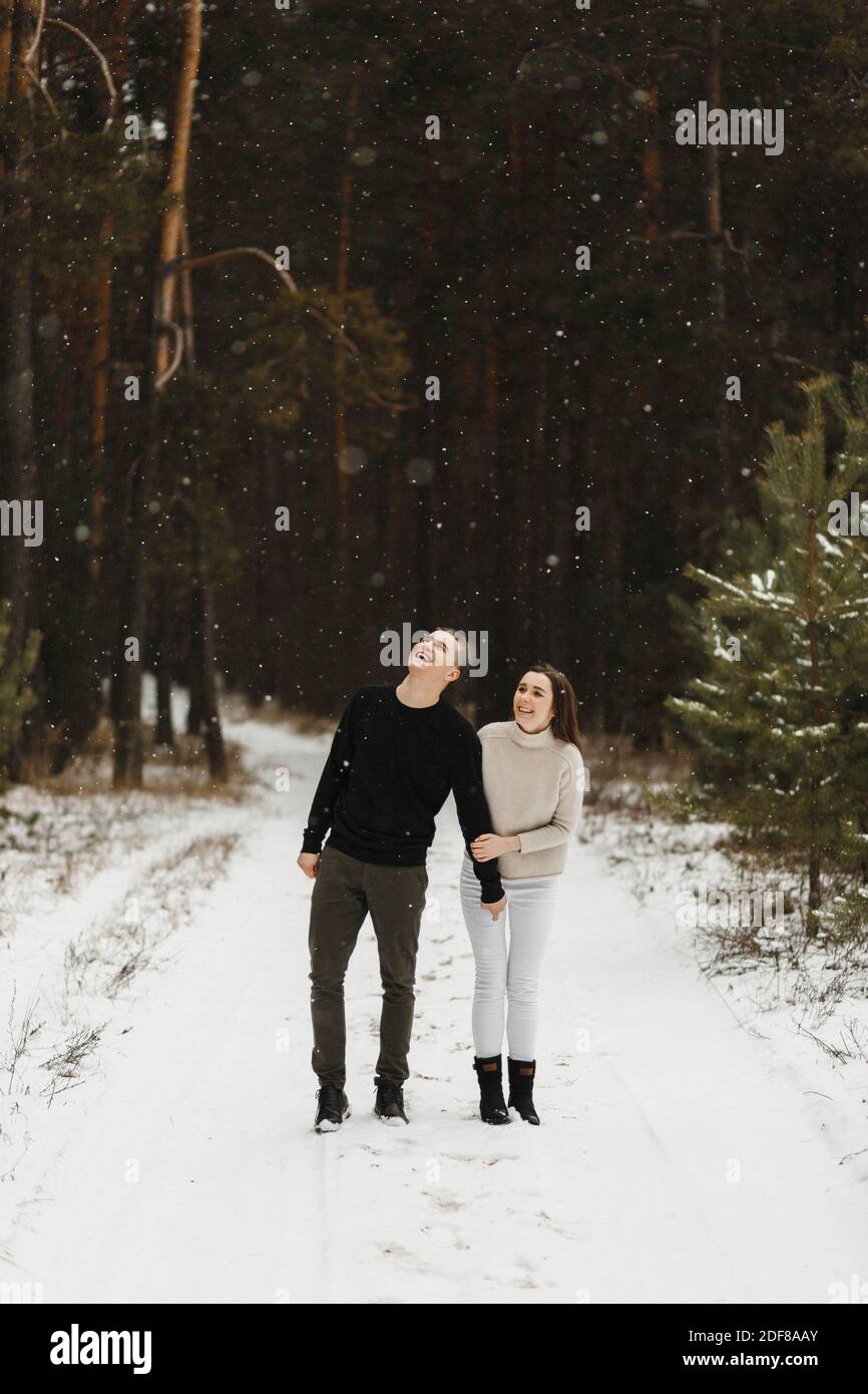 Lächelndes junges Paar auf dem Schnee im Winterwald mit Platz für Ihren Text. Liebe, Beziehung, Winterurlaub. Winter paar Foto-Ideen Stockfoto