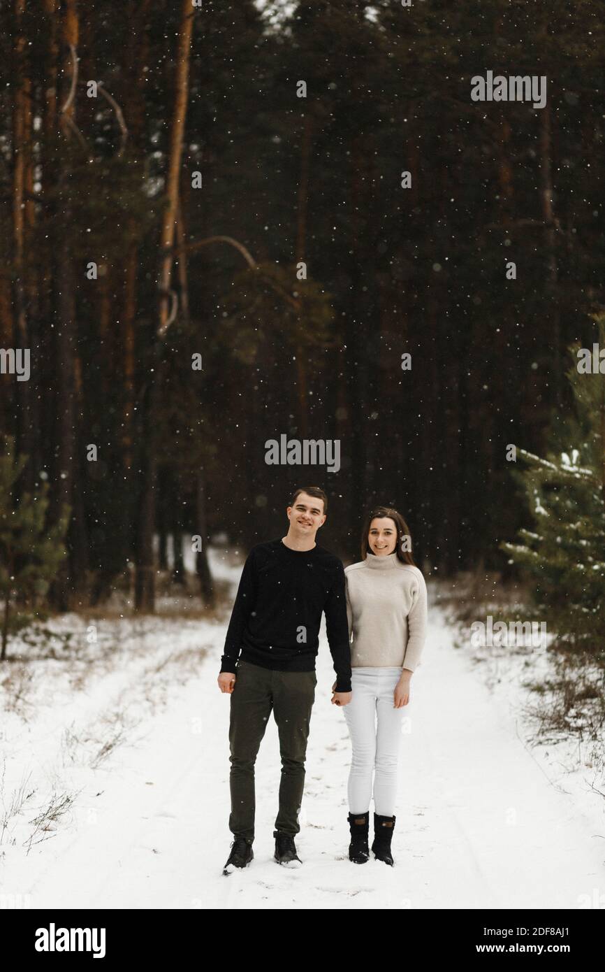 Lächelndes junges Paar zu Fuß im Winterwald mit Platz für Ihren Text. Liebe, Beziehung, Winterurlaub. Winter paar Foto-Ideen Stockfoto