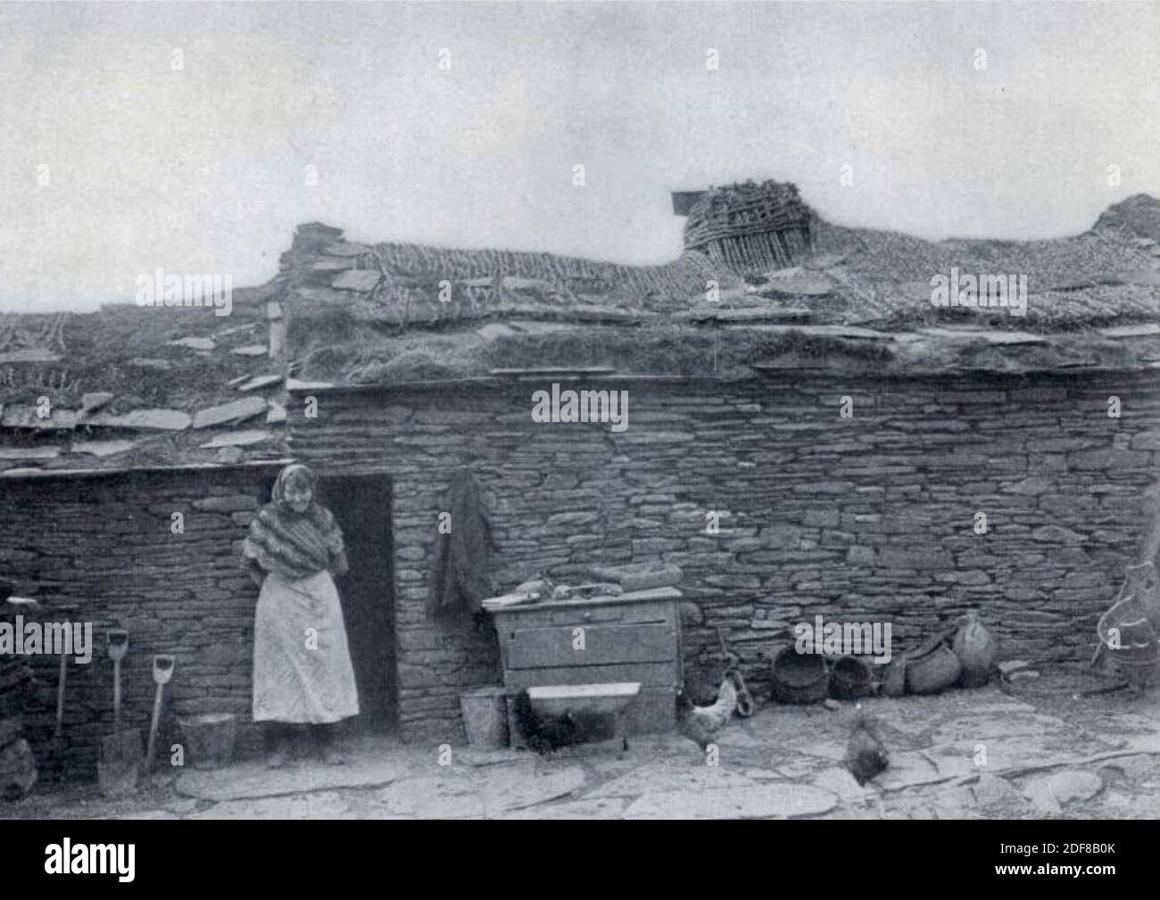 Vintage-Foto einer Frau, die vor ihrem Häuschen in Schottland steht. Stockfoto