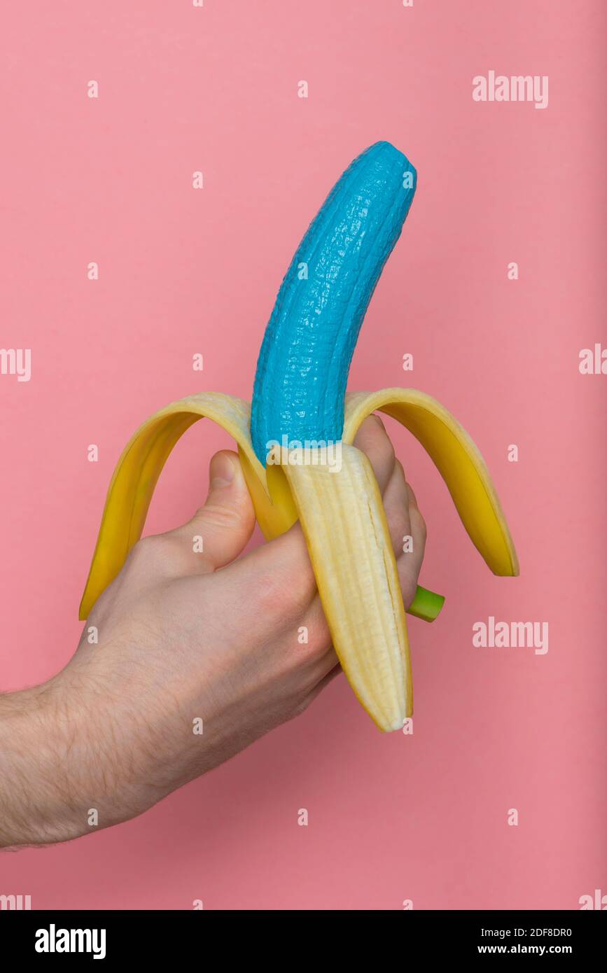 Blaue Banane in der Hand des Mannes auf rosa Hintergrund. Tapete im Hipster-Stil. Mode und Beauty Konzept. Stockfoto