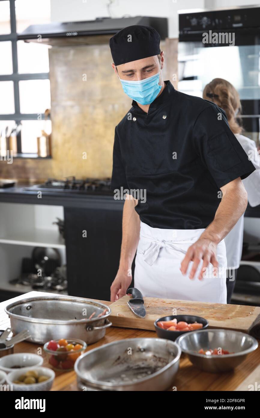 Kaukasischer Chefkoch mit Gesichtsmasken in der Küche Stockfoto