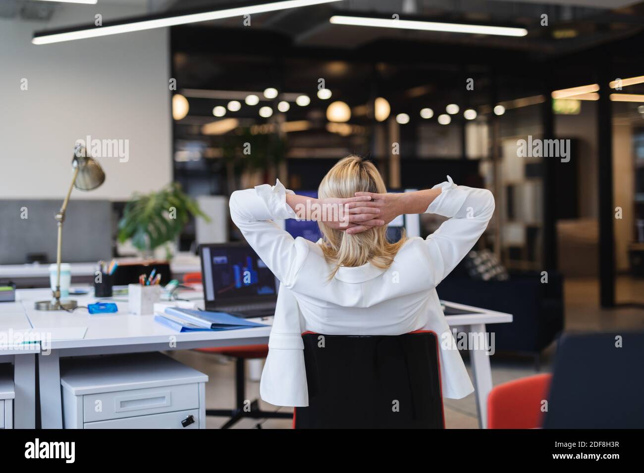 Rückansicht der kaukasischen Frau in kreativem Büro, Hände auf Kopf ruhend Stockfoto