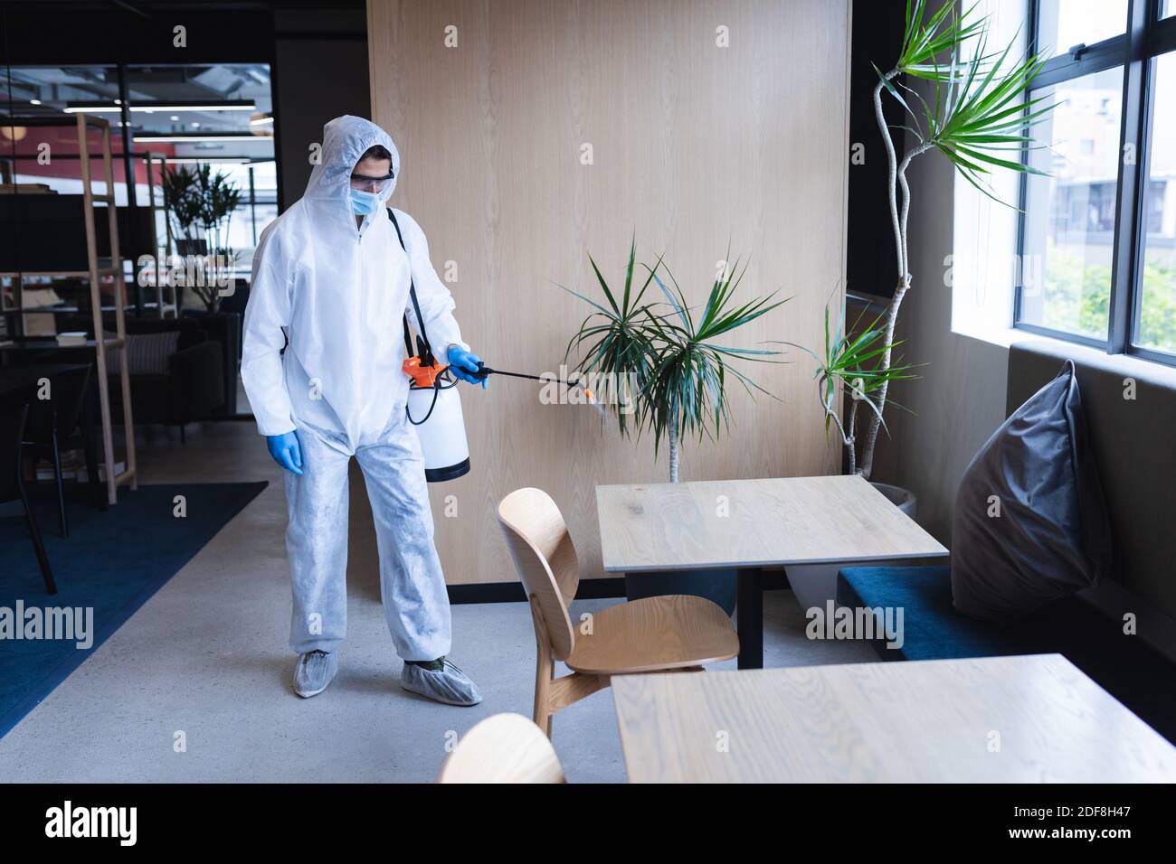 Gesundheitsarbeiter in Schutzkleidung Sprühen Desinfektionsmittel im Büro Stockfoto
