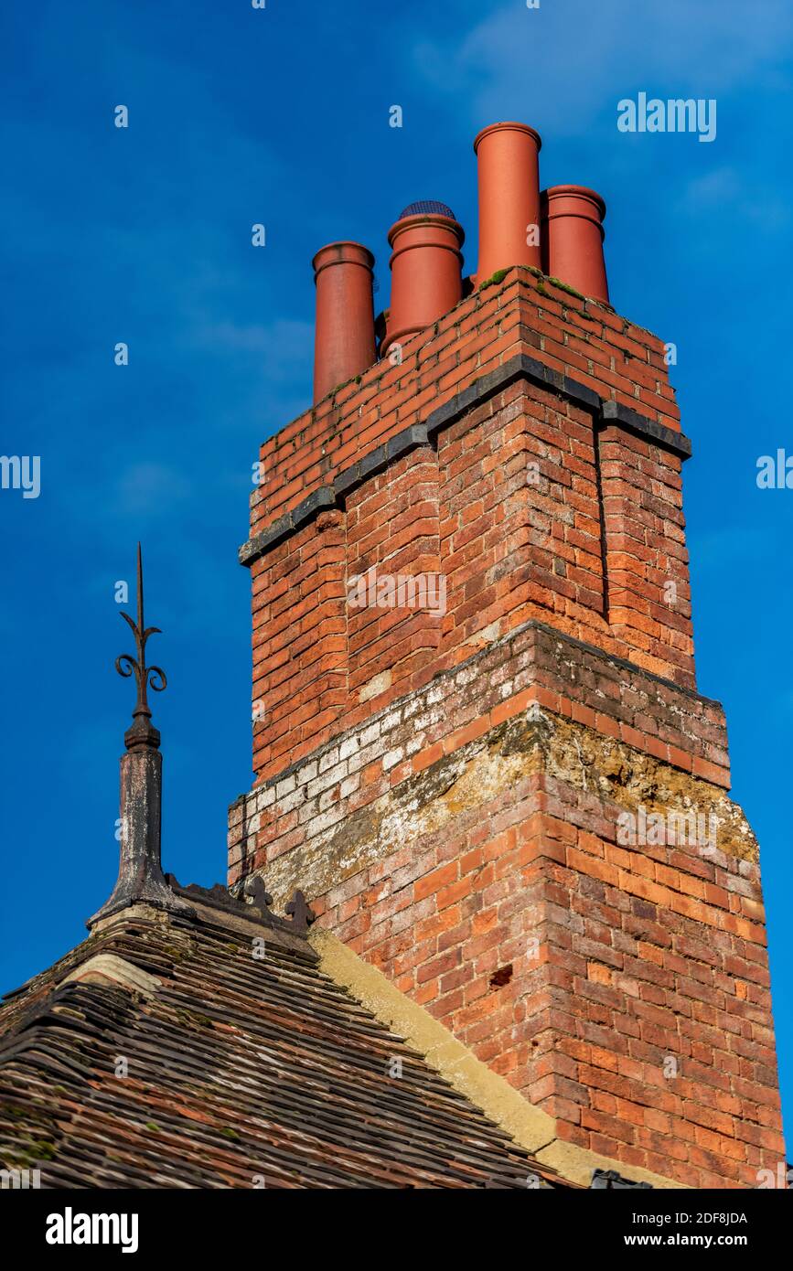 Traditionell gebaut roten Backstein Schornstein Stapel und Terrakotta-Kamin Töpfe auf einem viktorianischen Gebäude mit einem gusseisernen Blitzableiter Finial. Stockfoto