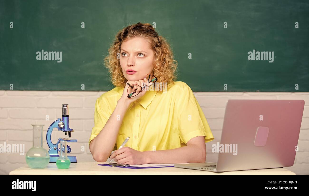 Wissenschaftler im Schullabor. Biologie-Experimentforschung. Denkender Student mit Mikroskop und Becher. Mädchen im Klassenraum mit Computer. Notizen zu den Forschungsergebnissen der Chemie machen. DNA Stockfoto