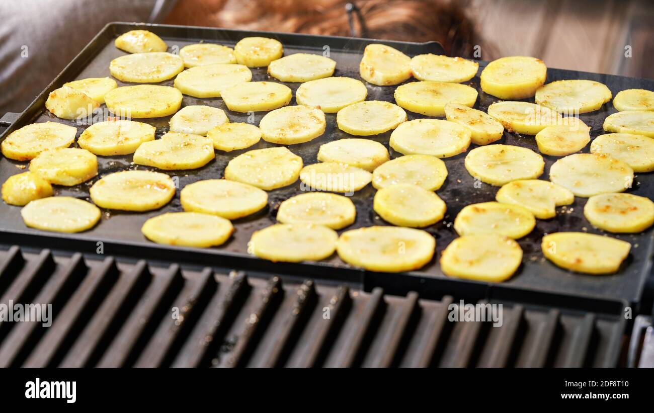 Kartoffel in kleine Kreise geschnitten, gewürzt mit Gewürzen, gegrillt auf elektrischem Grill Stockfoto