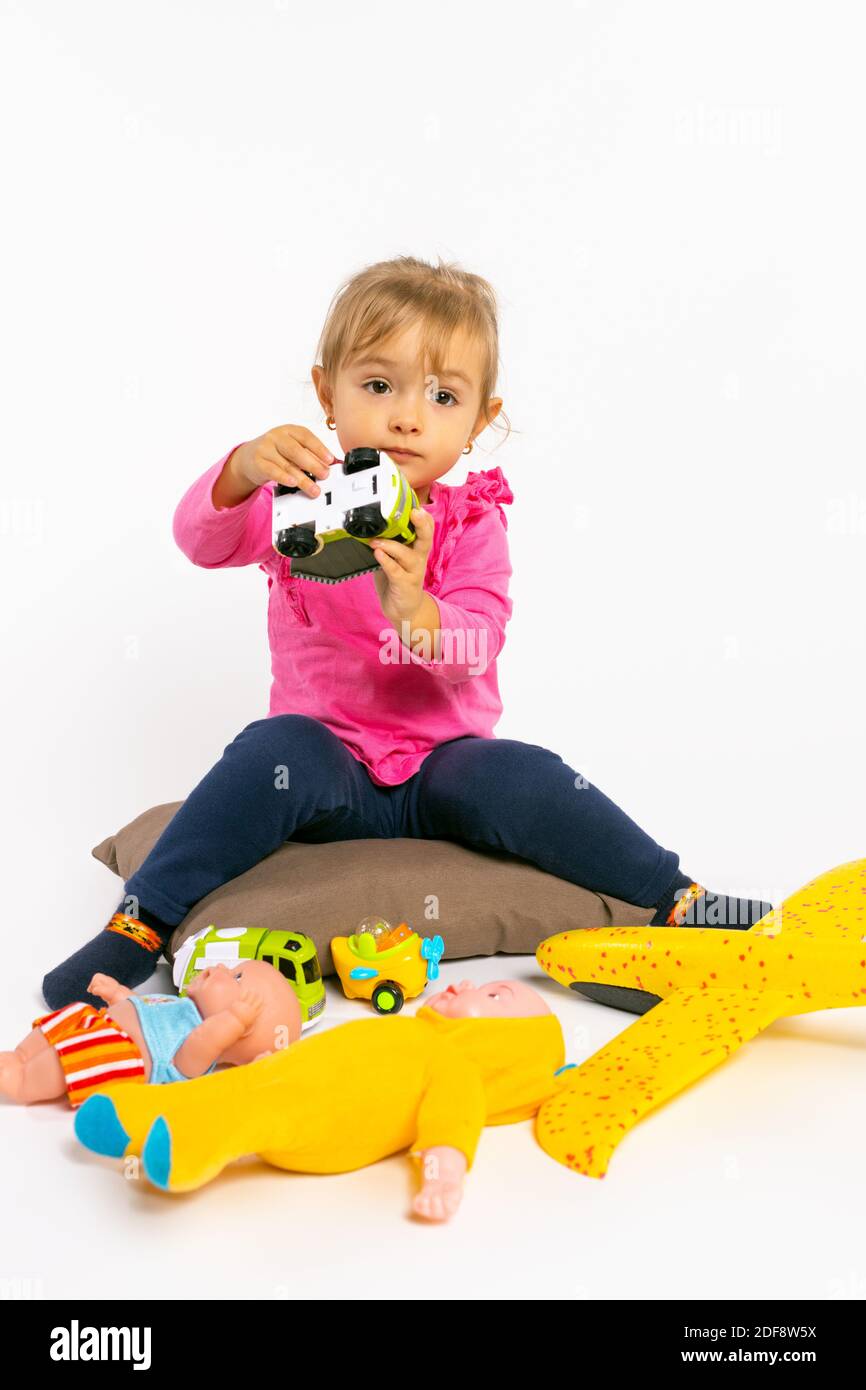 Kleinkind Mädchen spielt mit Jungen Spielzeug und schaut auf die Kamera. Geschlechterstereotypen. Stockfoto