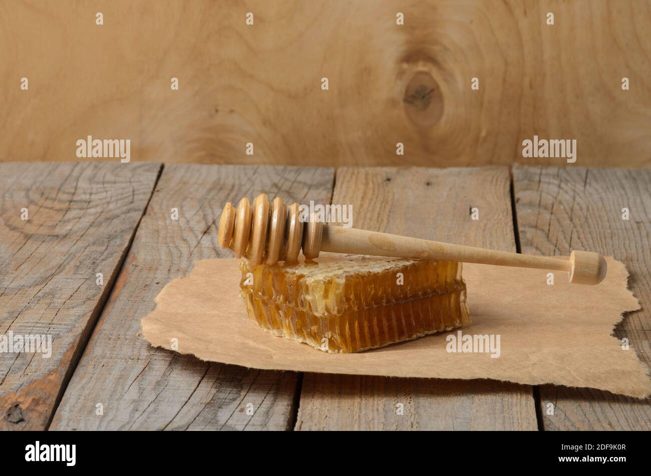 Honig in Waben und Löffel auf Geschenkpapier auf einem Holztisch. Selektiver Fokus. Stockfoto