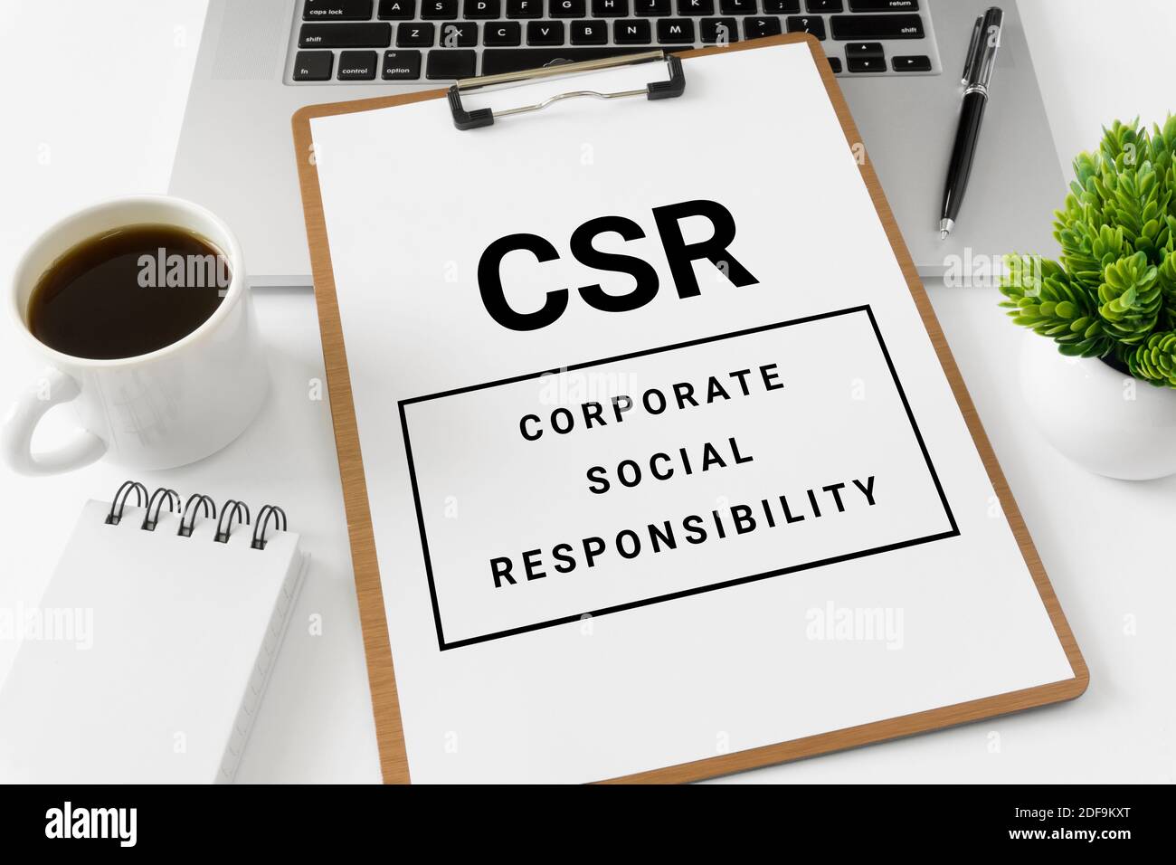 CSR Corporate Social Responsibility auf einem Whitepaper, das auf dem Laptop-Computer platziert ist. Stockfoto