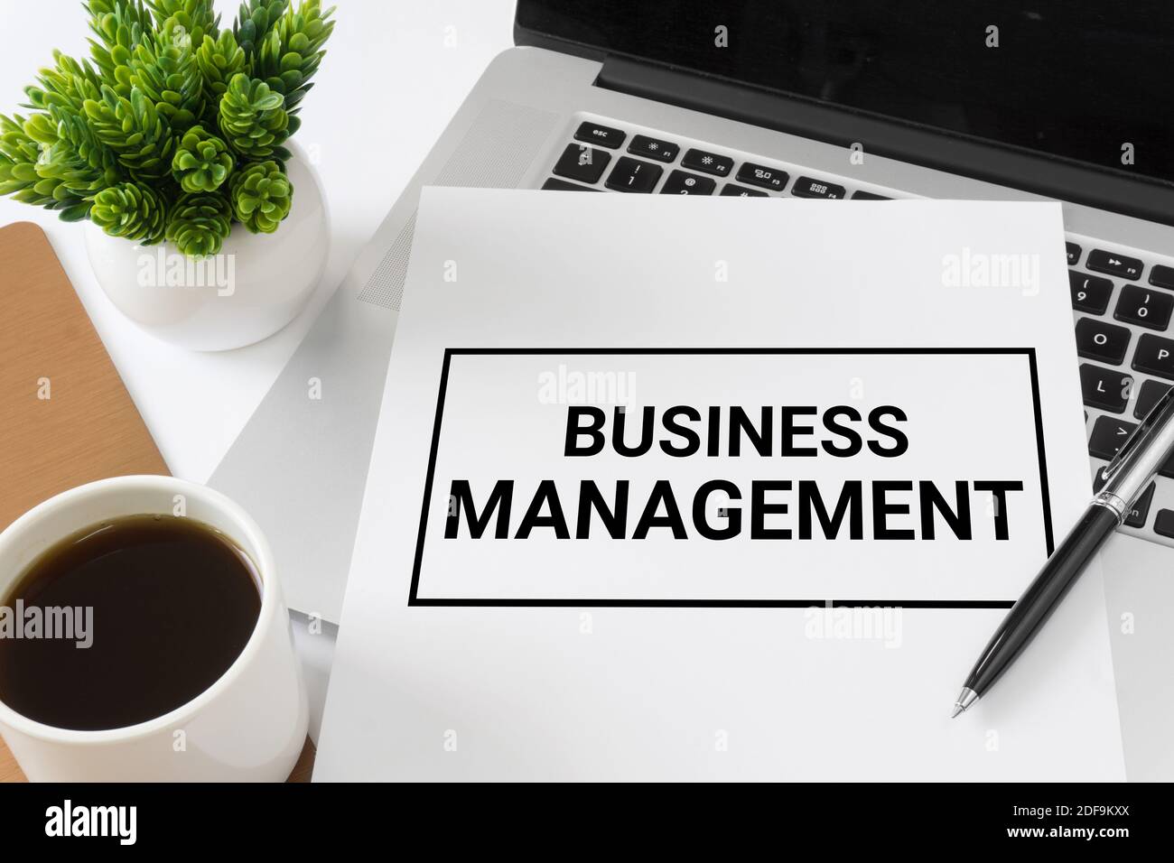 Business Management auf einem White Paper, das auf dem Laptop-Computer platziert wird. Geschäftskonzept. Stockfoto