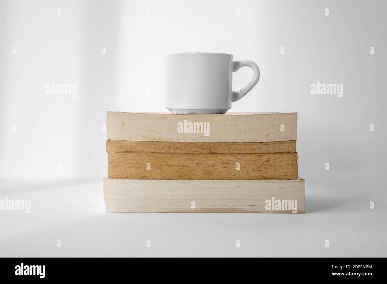 Kaffeetasse auf einem Stapel Bücher mit weißem Hintergrund. Stockfoto
