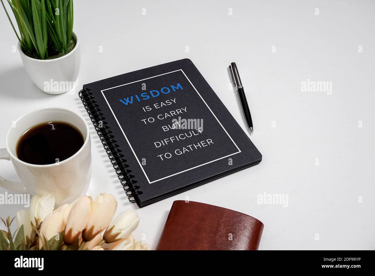 Notizbuch mit Weisheitszitat und Kaffeetasse auf weißem Hintergrund. Stockfoto