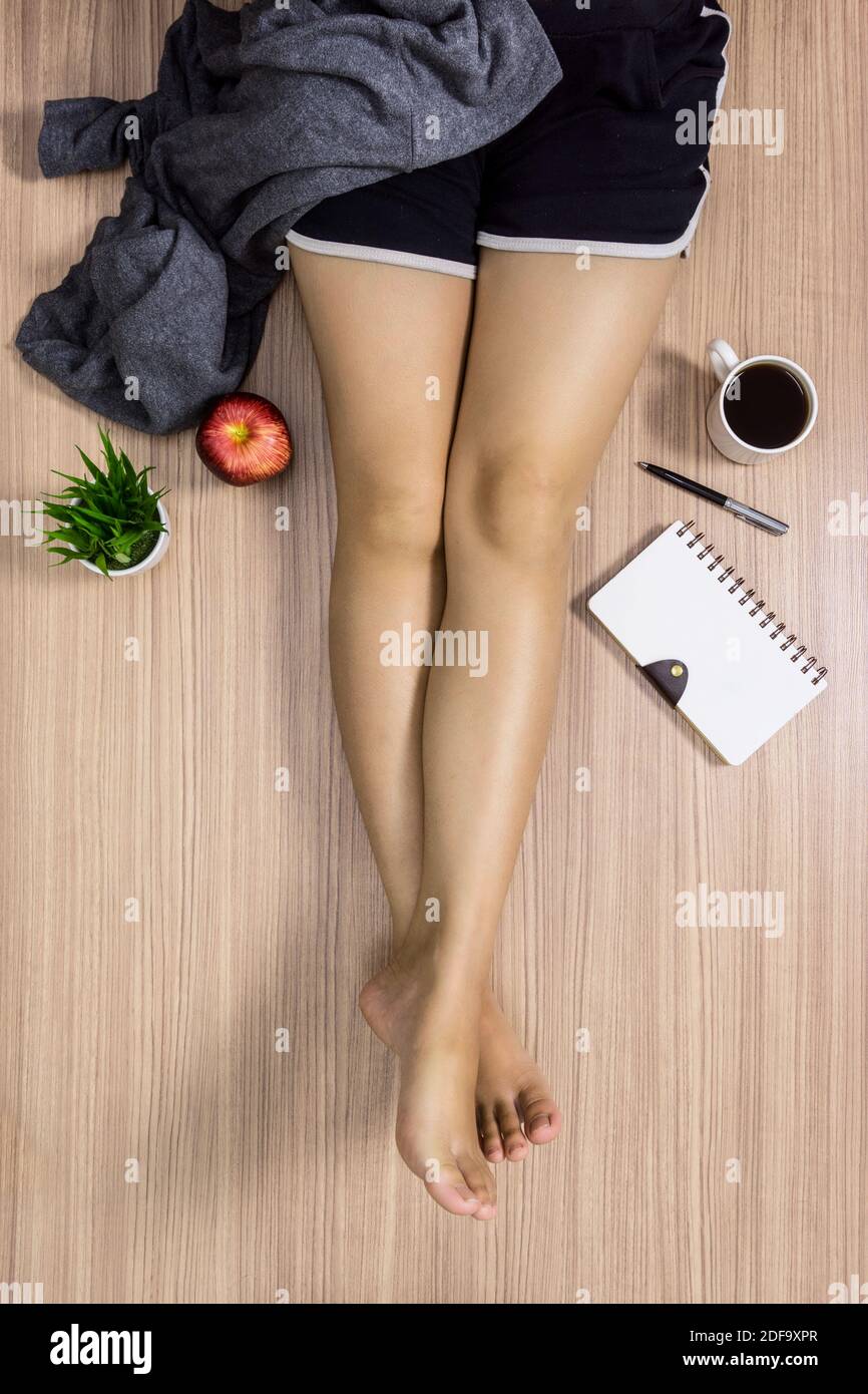 Junge Frau trägt kurze Hose auf Holzoberfläche sitzen. Häusliches Leben Lifestyle-Konzept. Stockfoto