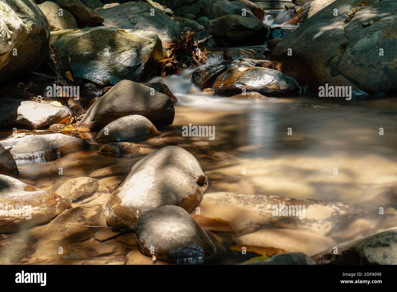 Ruhiger Bach mit Felsen, wunderschön von der Sonne gemalt. Stockfoto