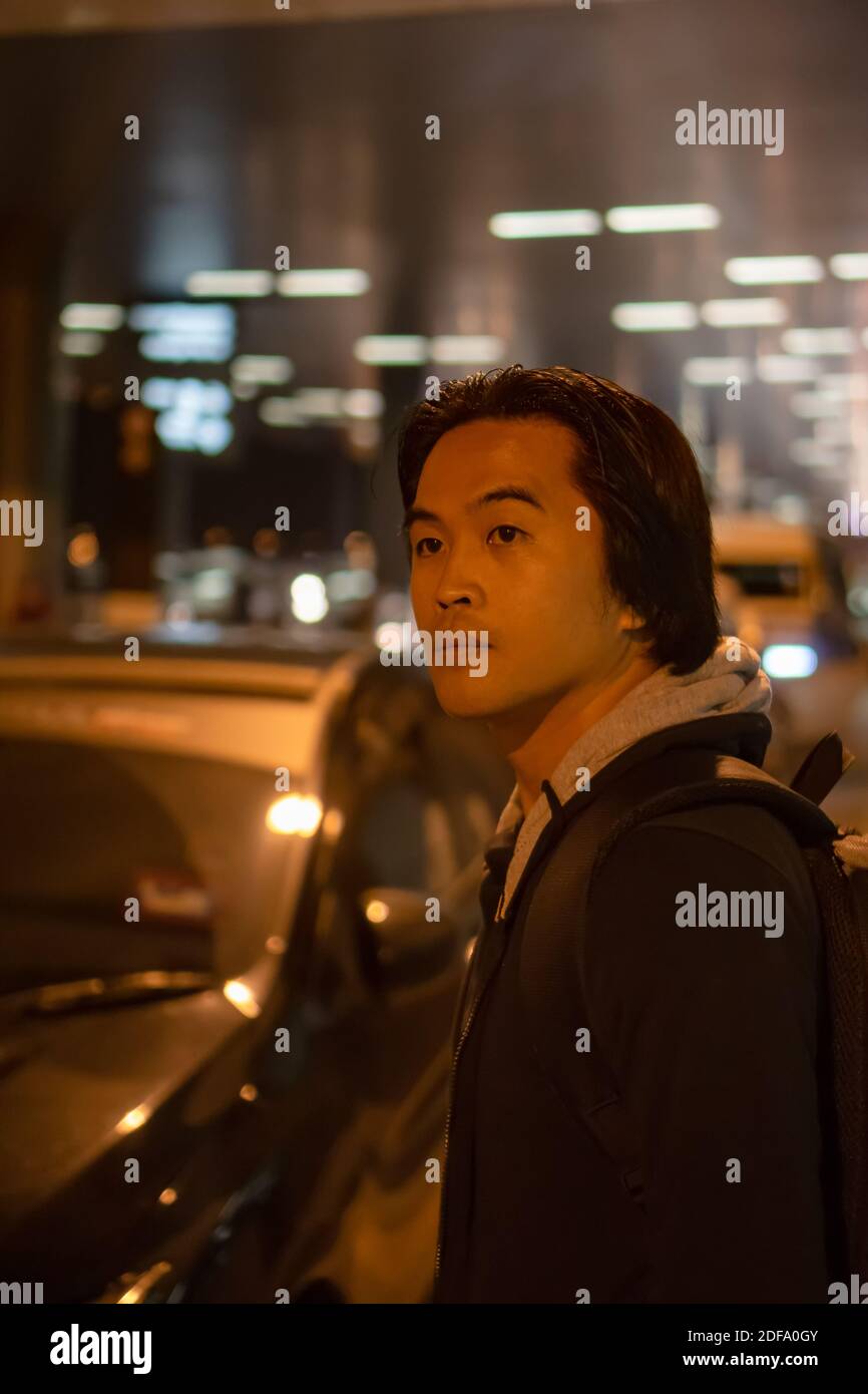Asiatischer Mann wartet auf seine Autofahrt in der Nacht in einem Flughafen. Stockfoto