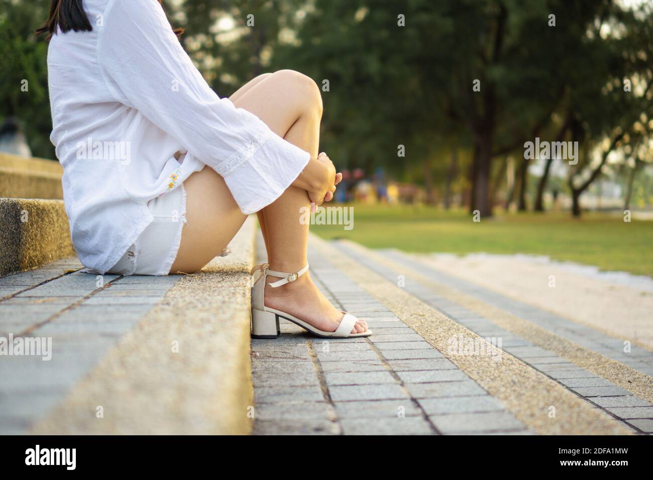 Frau sitzt auf Betontreppe im Park. Stockfoto