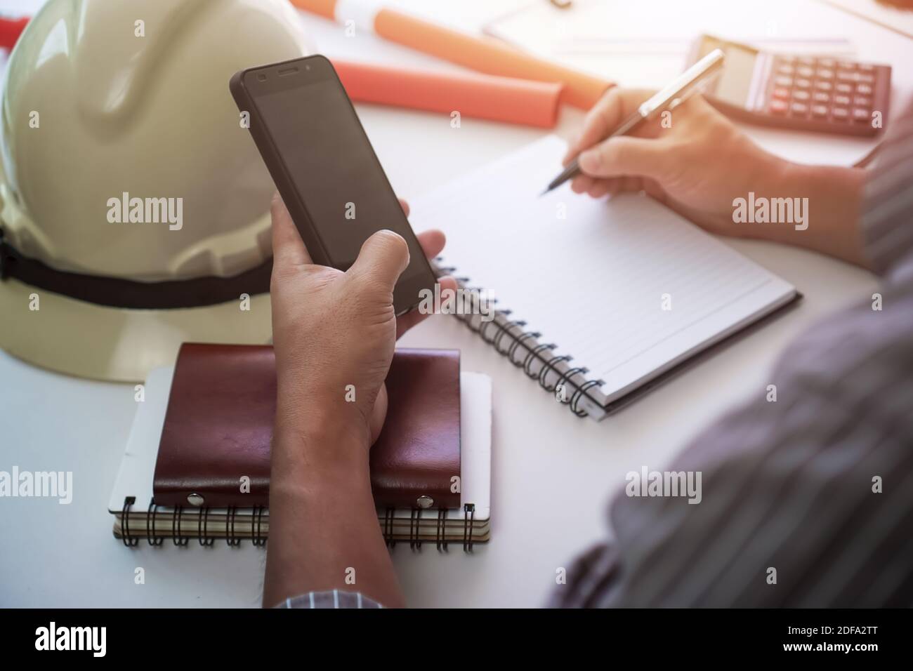 Mann, der auf dem Notizblock schreibt und das Telefon benutzt. Projektmanagement-Konzept. Stockfoto