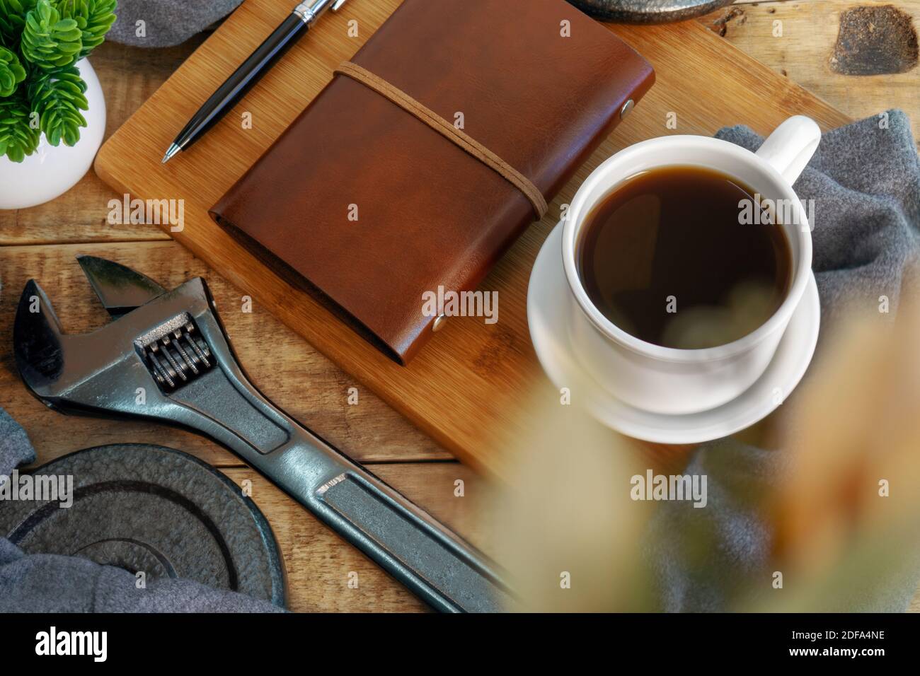 Schlüssel, Tagebuch und Kaffeetasse auf rustikalem Holzschreibtisch. Home Workshop. Stockfoto