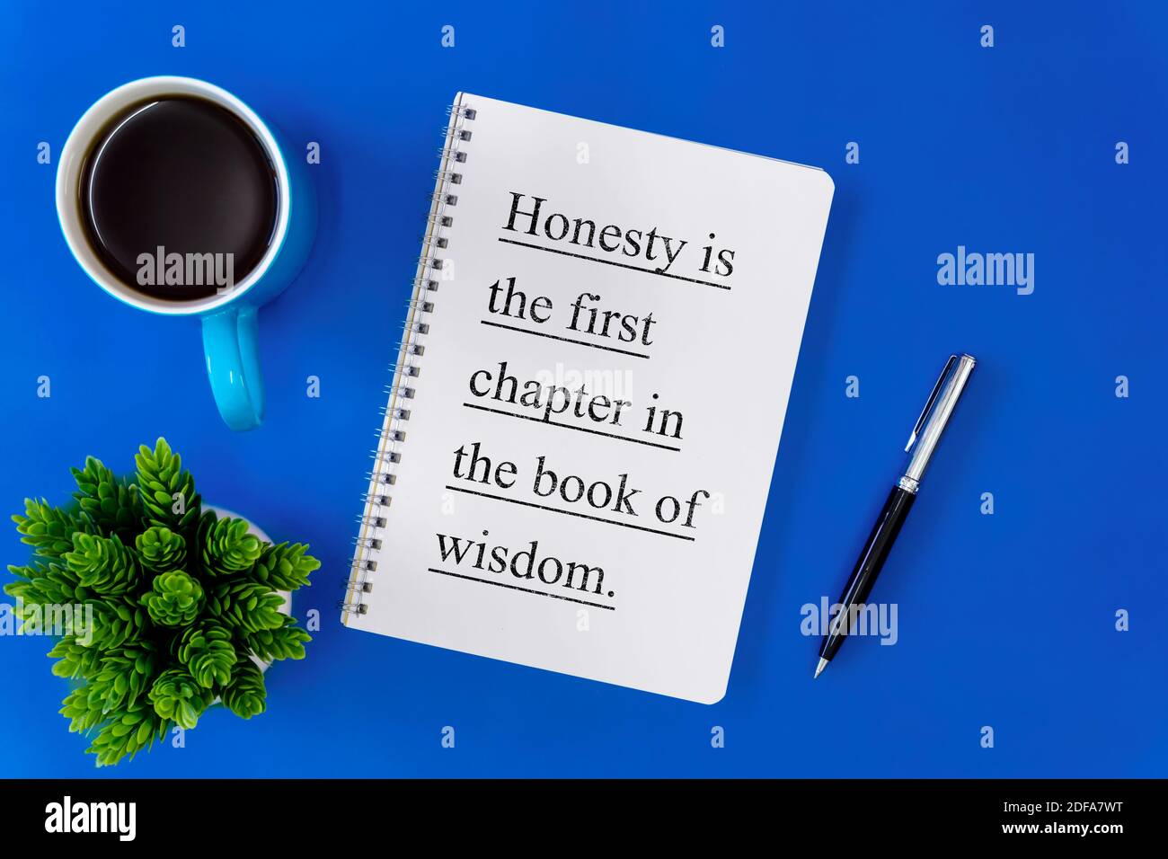 Notizbuch, Stift und Kaffeetasse auf blauem Hintergrund. Inspirierendes Lebenszitat auf Notizblock. Stockfoto