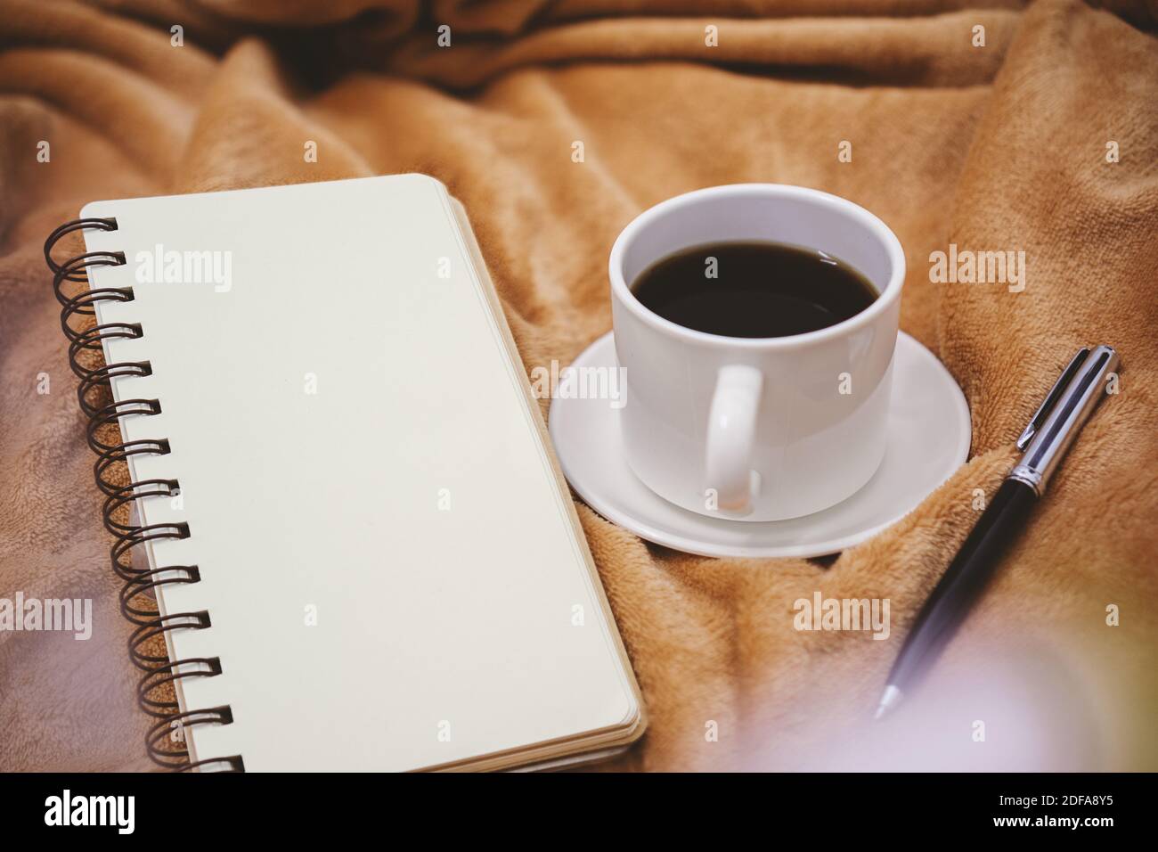 Selektive Fokusansicht von Notizbuch, Stift und Kaffeetasse auf der Decke. Stockfoto