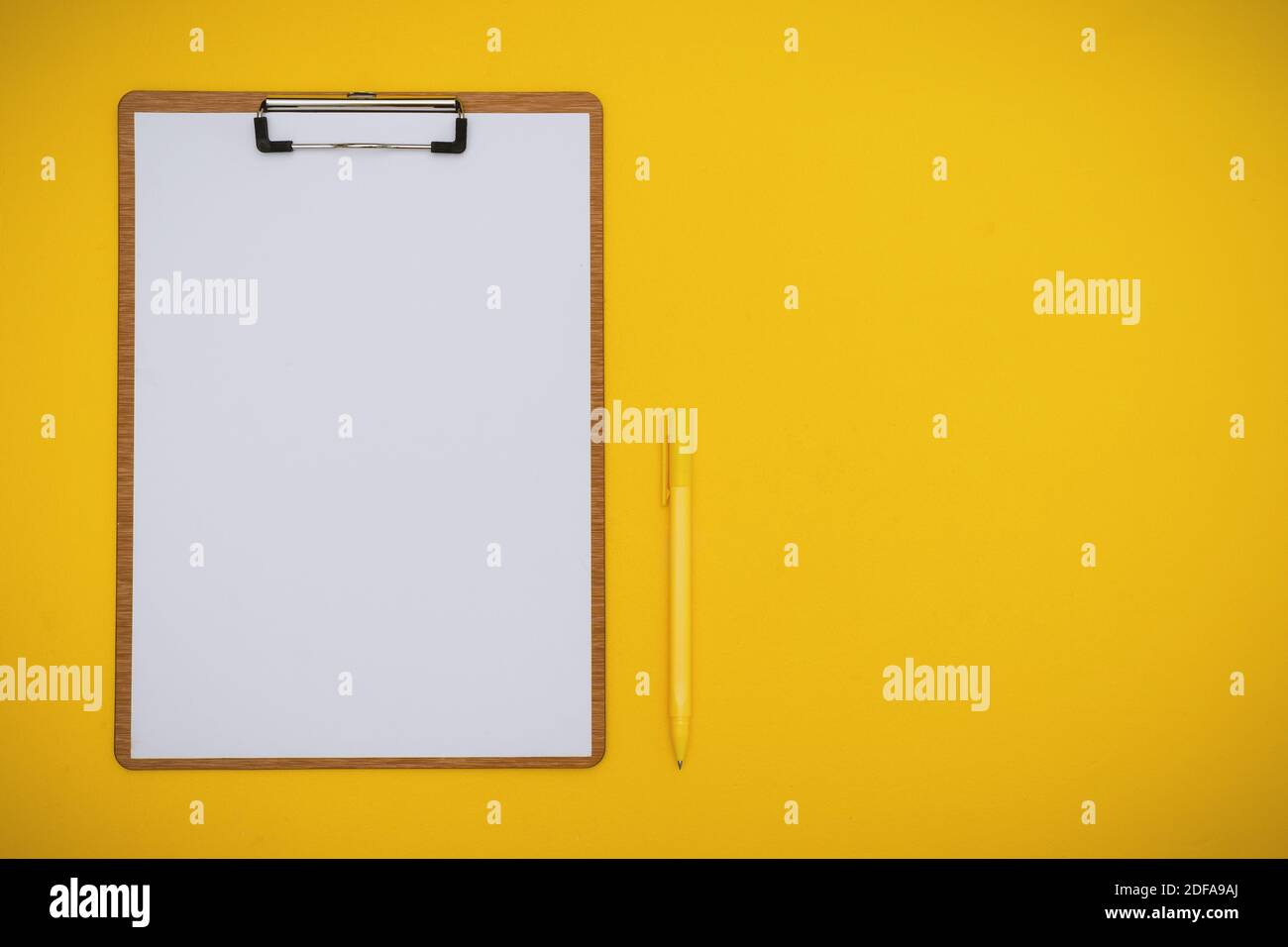 Overhead-Ansicht von Papier in Zwischenablage und Stift auf Gelb Hintergrund Stockfoto
