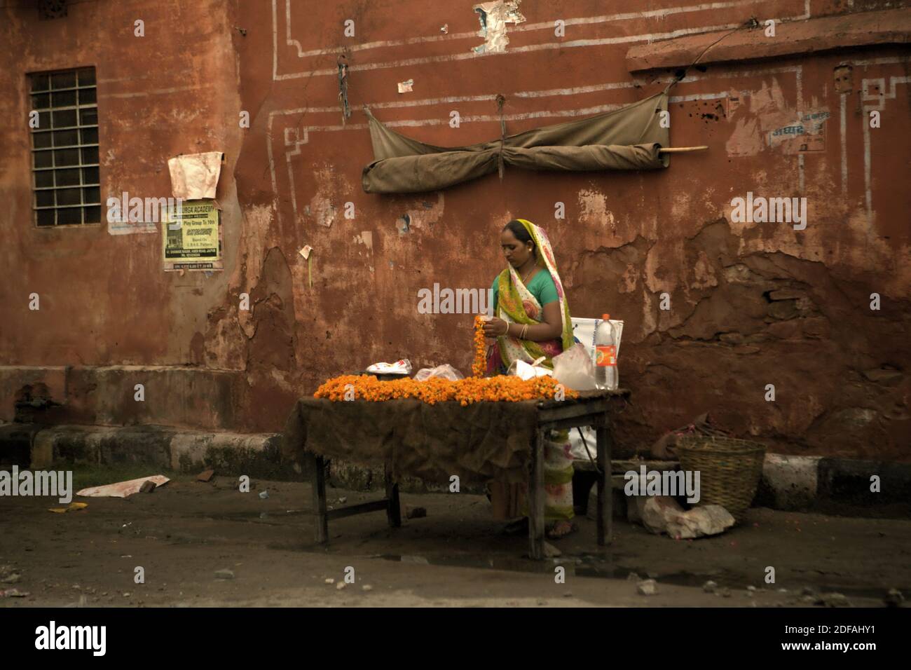 Eine Frau organisiert Blumen an ihrem Straßenrand Stand in Jaipur, Rajasthan, Indien. Stockfoto